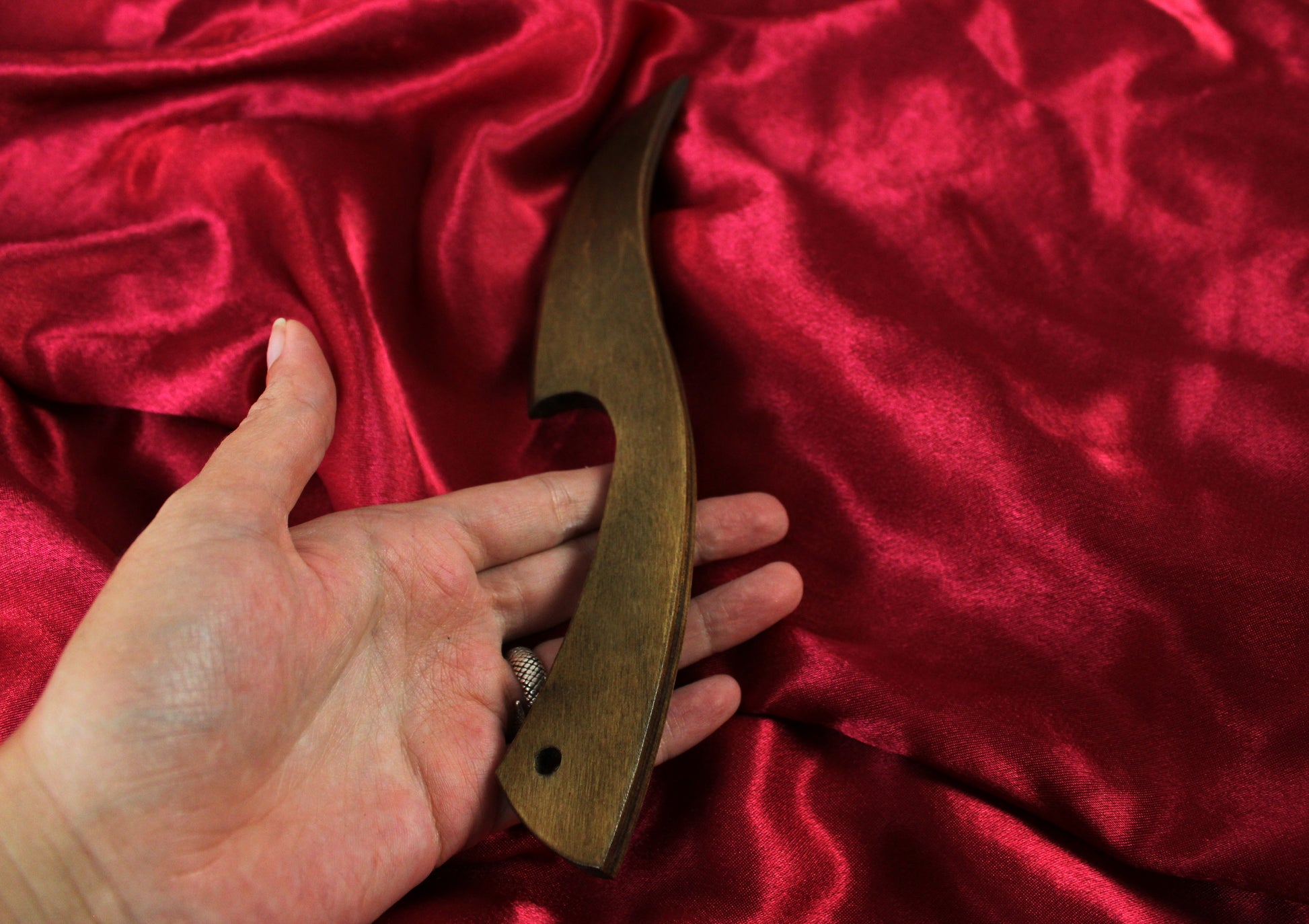 couteau bdsm en bois posé sur une main