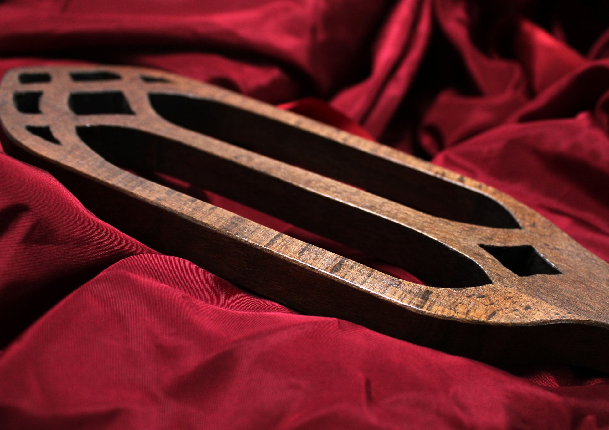 paddle en bois de style cathédrale, vue en partie de côté avec découpes ogives, sur fond de satin bordeaux