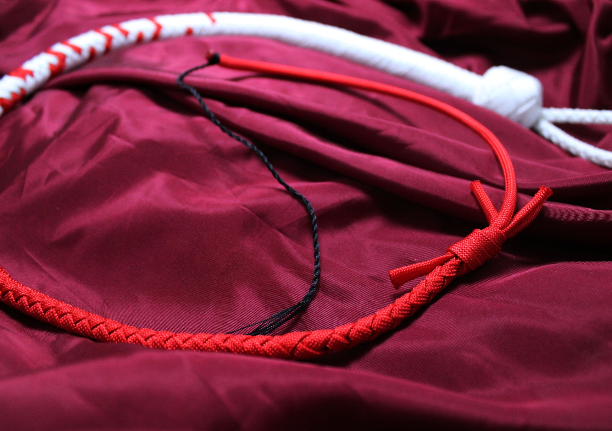 fouet blanc et rouge avec détail du tressage de la partie rouge