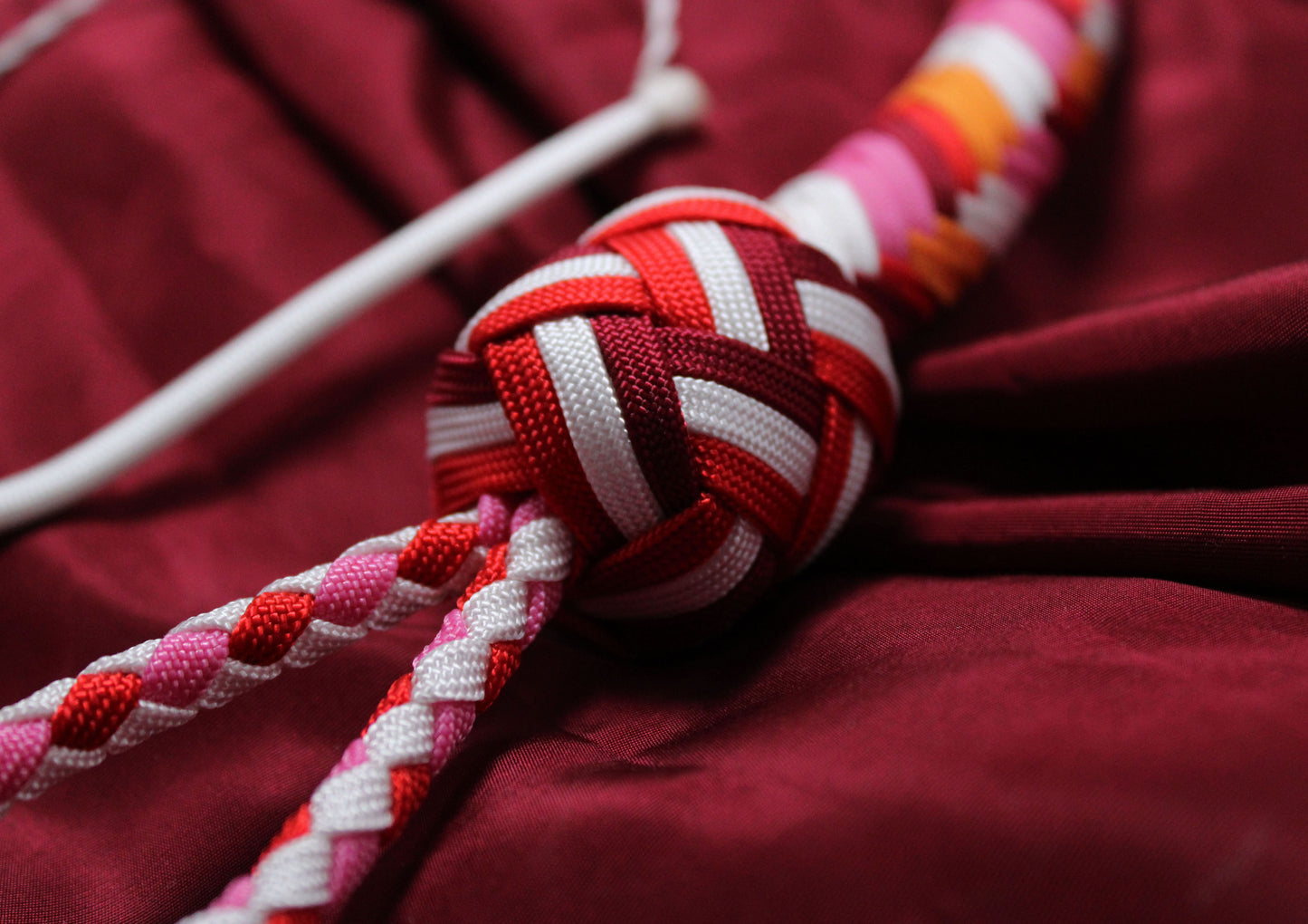 détail du knot aux couleurs du drapeau lesbien, alternance de rouge, blanc et bordeaux